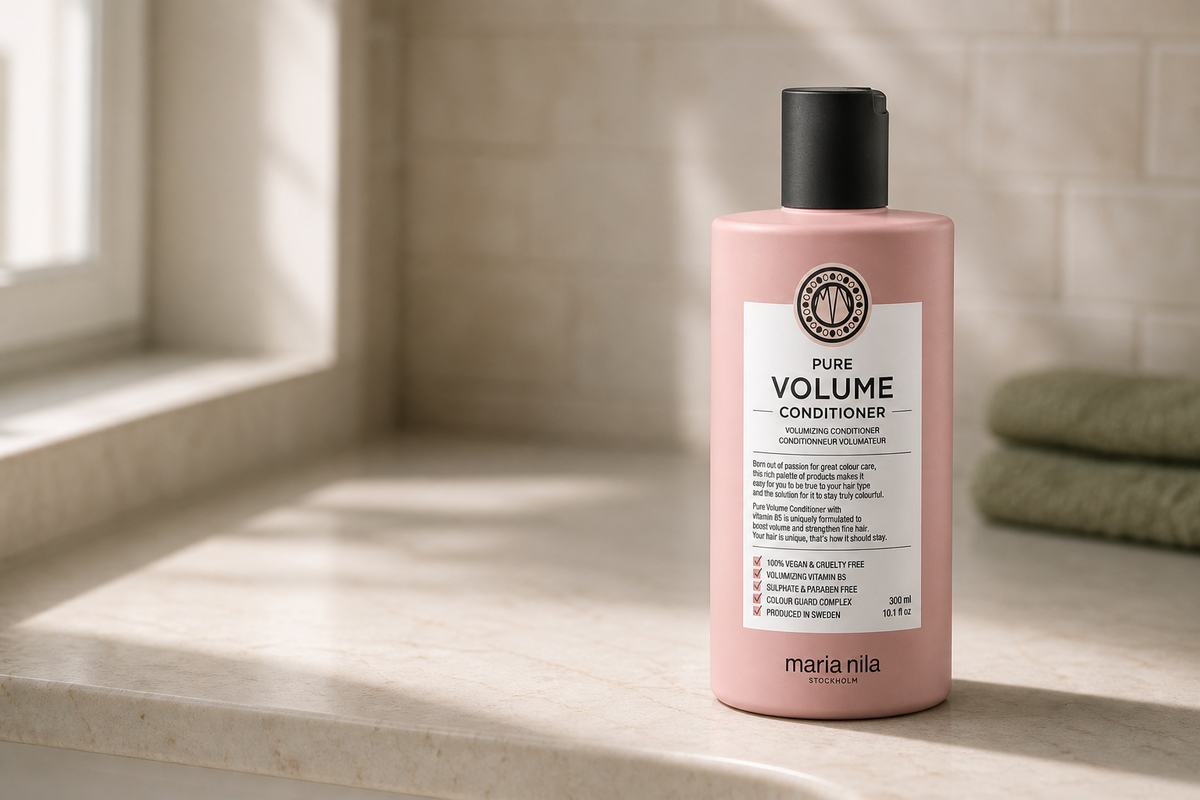 Balsam Maria Nila Pure Volume de 300 ml, așezat pe o poliță de marmură deschisă din baie, cu eticheta spre cameră și lumină laterală de la fereastră