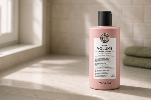 Balsam Maria Nila Pure Volume de 300 ml, așezat pe o poliță de marmură deschisă din baie, cu eticheta spre cameră și lumină laterală de la fereastră